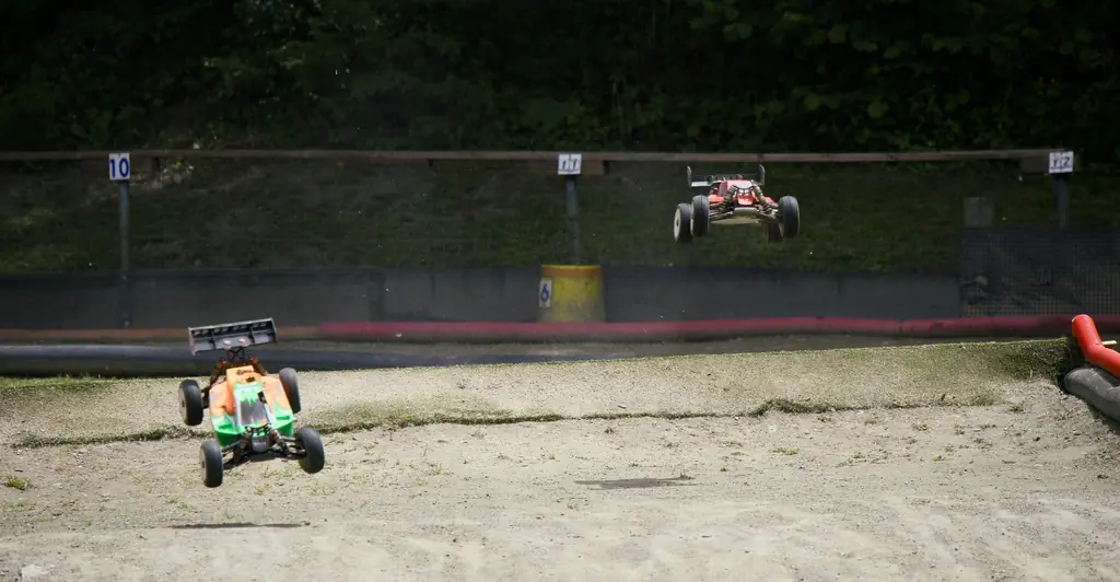 Deux buggys RC franchissant une bosse, l'un décollant derrière l'autre